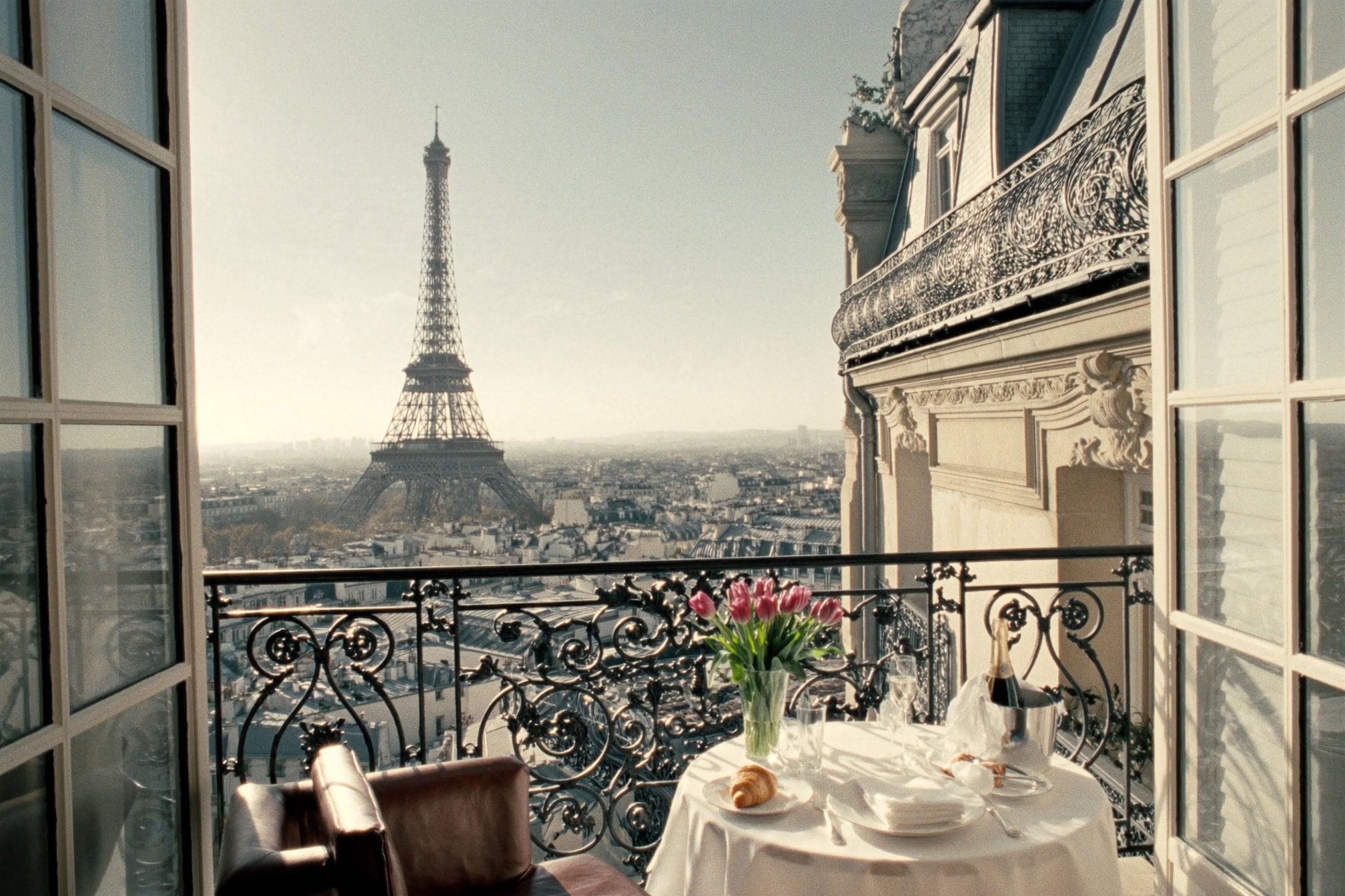 View of the Eiffel Tower from a Parisian balcony with a table set for breakfast